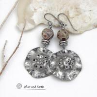 These handcrafted earrings have a bold edgy vibe. They feature rustic hammered silver tone pewter dangles accented with natural asteroid jasper stones and stainless steel beads. This type of stone is known for its unique dotted matrix in earth-tone hues of brown, gray and tan. Bold and striking - they're sure to make a statement. Perfect for women that love unique natural stones and artisan handmade jewelry. Handmade in the USA by Silver and Earth Jewelry. 