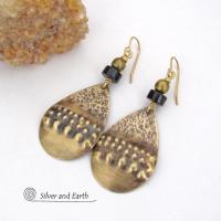 These handcrafted earrings feature gold brass teardrop dangles with a rustic hammered and hand stamped texture accented with matte black jasper stones and brass beads. They have an exotic, bohemian tribal vibe that makes a bold statement. Perfect for women that love to wear unique artisan handcrafted jewelry. Handmade in the USA by Silver and Earth Jewelry. 