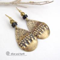 These handcrafted earrings feature gold brass teardrop dangles with a rustic hammered and hand stamped texture accented with matte black jasper stones and brass beads. They have an exotic, bohemian tribal vibe that makes a bold statement. Perfect for women that love to wear unique artisan handcrafted jewelry. Handmade in the USA by Silver and Earth Jewelry. 