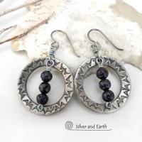 These handcrafted silver pewter hoop earrings have a hand stamped texture accented with black lava rock stones dangling in front. The stones have natural "pits" and crevices which is expected with porous lava stones. Lava stone is formed when molten rock erupts from an active volcano and comes in contact with the cool atmosphere of the Earth, which begins to solidify it. They have an earthy chic style that coordinates with all wardrobe types.