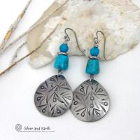 These handcrafted earrings feature silver pewter teardrop-shaped dangles with a hand stamped texture accented with natural turquoise stones and stainless steel spacer beads. They have a bold modern style with southwestern flair and will make a striking statement. They'll make a great gift for anyone that loves natural turquoise stones and southwest style jewelry. Handmade in the USA by Silver and Earth Jewelry, a New Mexico True Certified business. 