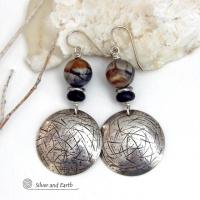These one-of-a-kind earrings feature handcrafted sterling silver with a hammered and hand stamped texture accented with earthy natural Picasso marble gemstones, black glass and stainless steel beads. This semiprecious stone is found only in southwest Utah. It's named after the famous artist because the natural matrix of geometric lines resembles an abstract painting. The stones in this pair have a beautiful matrix pattern of distinctive swirly lines in black, grey and chocolate brown.
