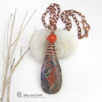 This handcrafted pendant necklace features a natural rhyolite jasper stone wire wrapped in copper wire and accented with a nugget-shaped coral bead. It has a natural pattern in several shades of earthy green along with splashes of orange. It has an earthy, casual boho style and is perfect for anyone that loves natural stones. It comes on an 18” copper chain with sturdy hook & eye closure; which can be removed from the pendant and worn alone or with other pendants in your wardrobe.