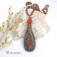 This handcrafted pendant necklace features a natural rhyolite jasper stone wire wrapped in copper wire and accented with a nugget-shaped coral bead. It has a natural pattern in several shades of earthy green along with splashes of orange. It has an earthy, casual boho style and is perfect for anyone that loves natural stones. It comes on an 18” copper chain with sturdy hook & eye closure; which can be removed from the pendant and worn alone or with other pendants in your wardrobe.