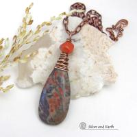 This handcrafted pendant necklace features a natural rhyolite jasper stone wire wrapped in copper wire and accented with a nugget-shaped coral bead. It has a natural pattern in several shades of earthy green along with splashes of orange. It has an earthy, casual boho style and is perfect for anyone that loves natural stones. It comes on an 18” copper chain with sturdy hook & eye closure; which can be removed from the pendant and worn alone or with other pendants in your wardrobe.