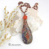 This handcrafted pendant necklace features a natural rhyolite jasper stone wire wrapped in copper wire and accented with a nugget-shaped coral bead. It has a natural pattern in several shades of earthy green along with splashes of orange. It has an earthy, casual boho style and is perfect for anyone that loves natural stones. It comes on an 18” copper chain with sturdy hook & eye closure; which can be removed from the pendant and worn alone or with other pendants in your wardrobe.