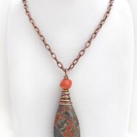 This handcrafted pendant necklace features a natural rhyolite jasper stone wire wrapped in copper wire and accented with a nugget-shaped coral bead. It has a natural pattern in several shades of earthy green along with splashes of orange. It has an earthy, casual boho style and is perfect for anyone that loves natural stones. It comes on an 18” copper chain with sturdy hook & eye closure; which can be removed from the pendant and worn alone or with other pendants in your wardrobe.