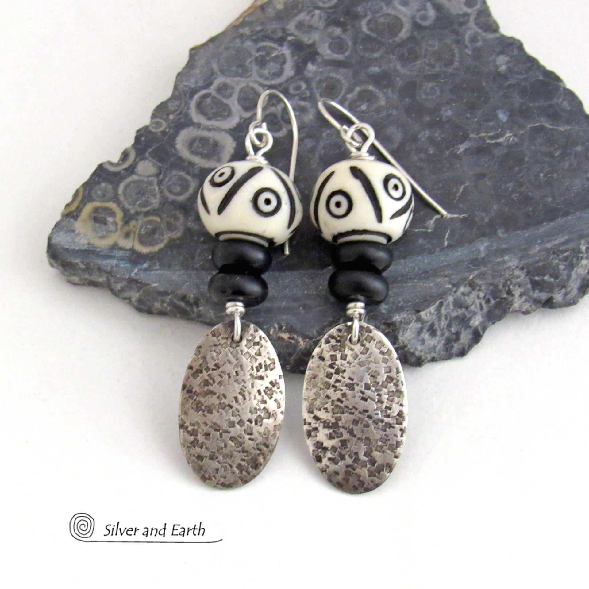 These handcrafted sterling silver earrings have a rustic, hand stamped texture and are accented with African carved bone and matte black agate beads. The bone beads have a bold, striking pattern of black circles and lines carved into a white base. Lightweight and fun to wear - they have an ethnic, tribal vibe and will make a unique statement.