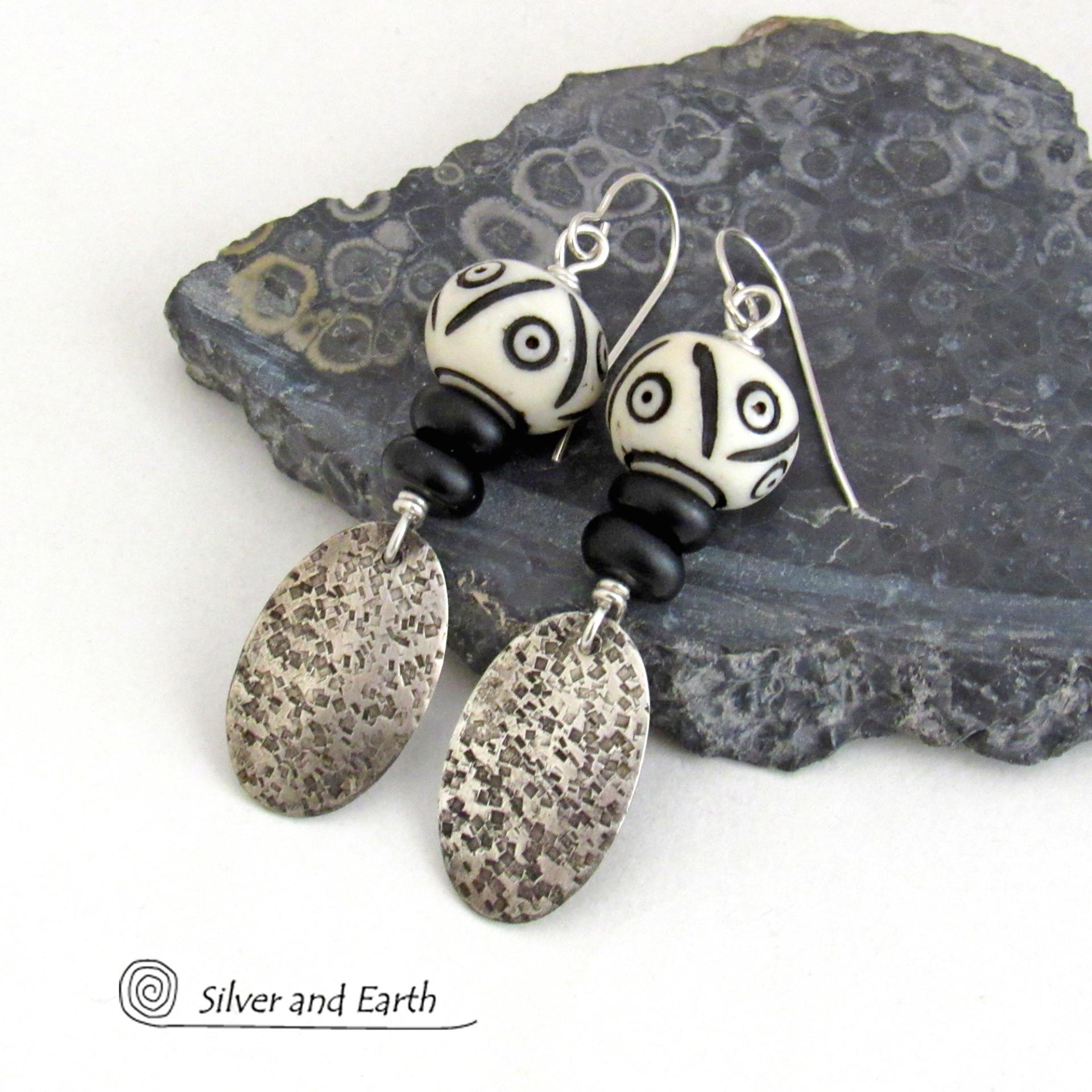 These handcrafted sterling silver earrings have a rustic, hand stamped texture and are accented with African carved bone and matte black agate beads. The bone beads have a bold, striking pattern of black circles and lines carved into a white base. Lightweight and fun to wear - they have an ethnic, tribal vibe and will make a unique statement.