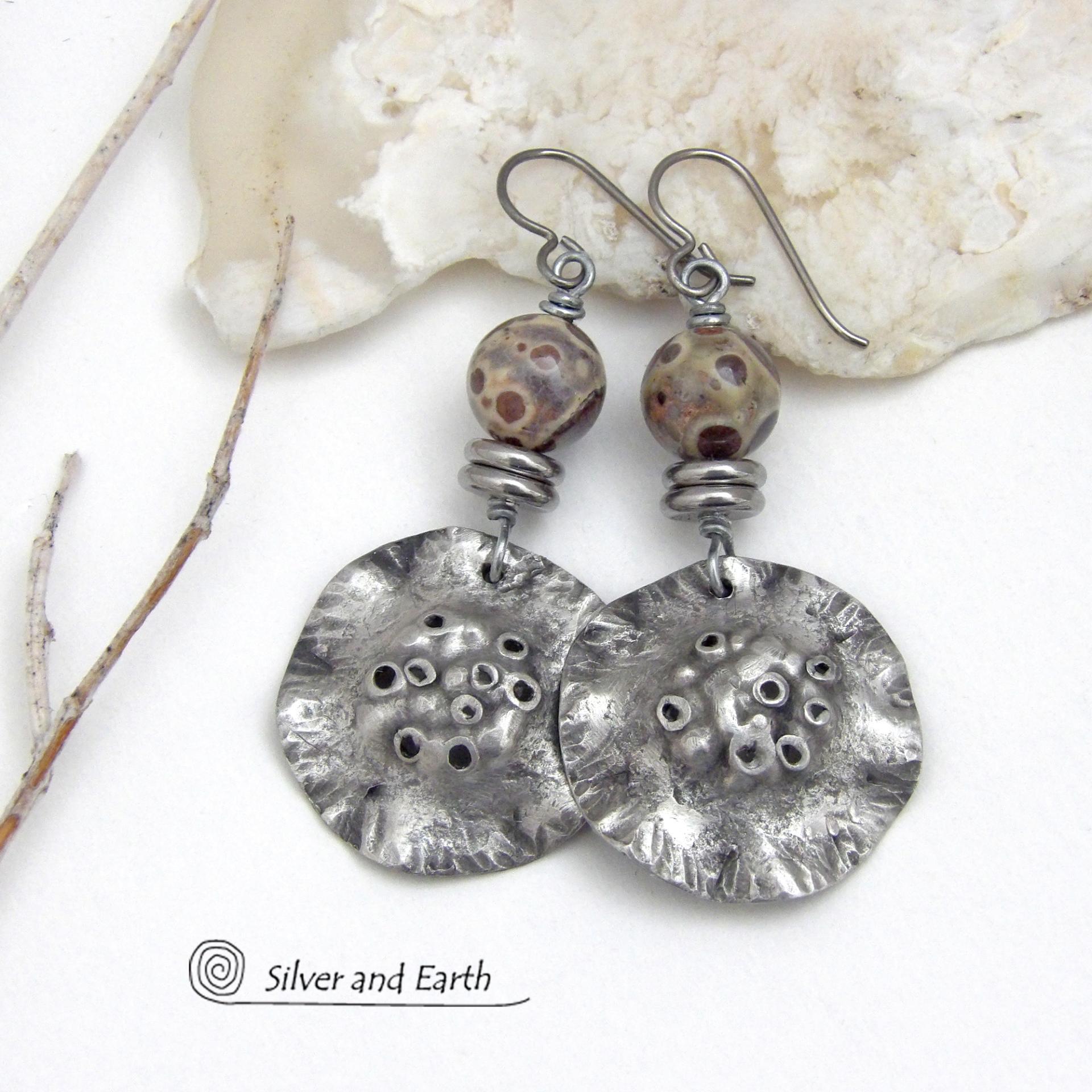 These handcrafted earrings have a bold edgy vibe. They feature rustic hammered silver tone pewter dangles accented with natural asteroid jasper stones and stainless steel beads. This type of stone is known for its unique dotted matrix in earth-tone hues of brown, gray and tan. Bold and striking - they're sure to make a statement. Perfect for women that love unique natural stones and artisan handmade jewelry. Handmade in the USA by Silver and Earth Jewelry. 