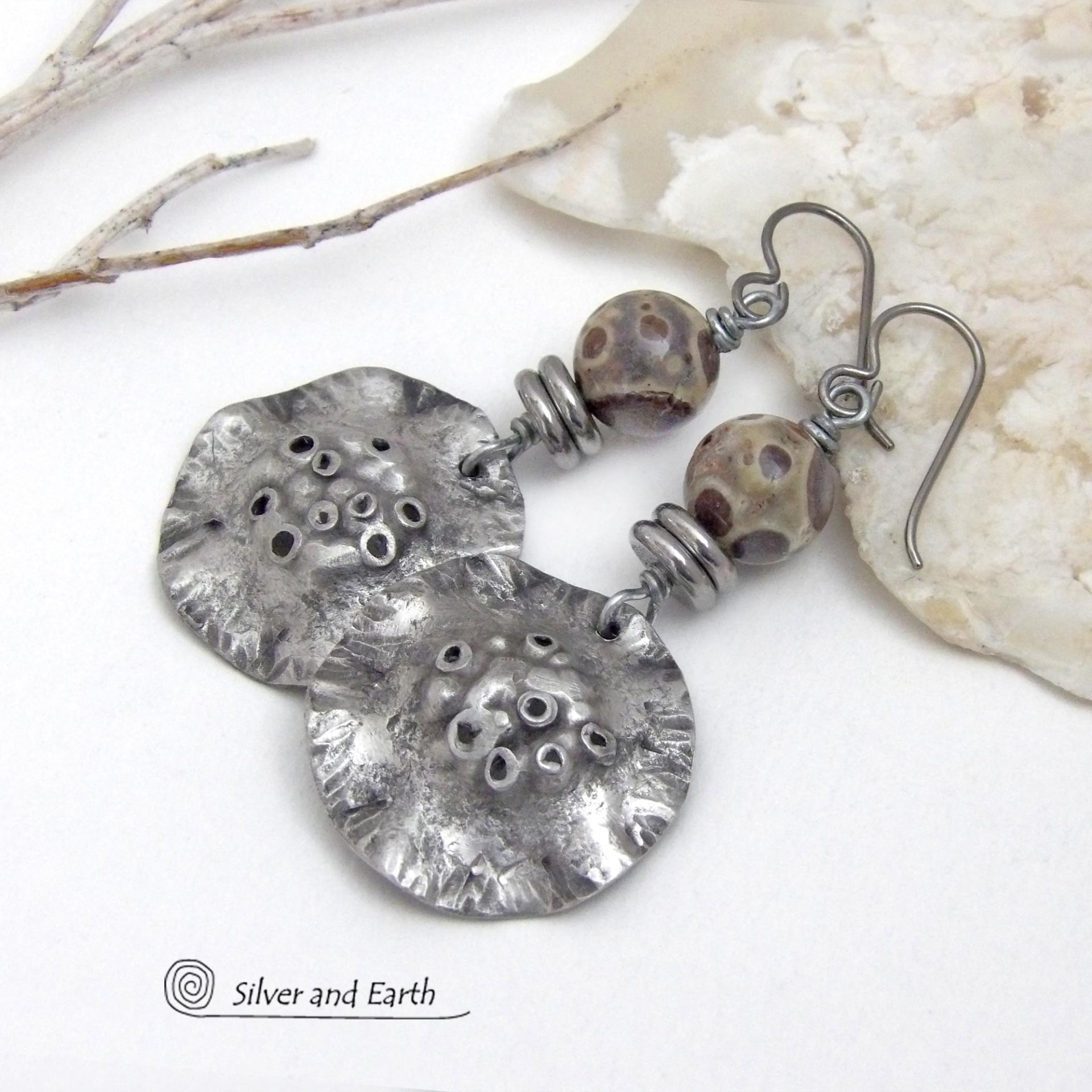 These handcrafted earrings have a bold edgy vibe. They feature rustic hammered silver tone pewter dangles accented with natural asteroid jasper stones and stainless steel beads. This type of stone is known for its unique dotted matrix in earth-tone hues of brown, gray and tan. Bold and striking - they're sure to make a statement. Perfect for women that love unique natural stones and artisan handmade jewelry. Handmade in the USA by Silver and Earth Jewelry. 