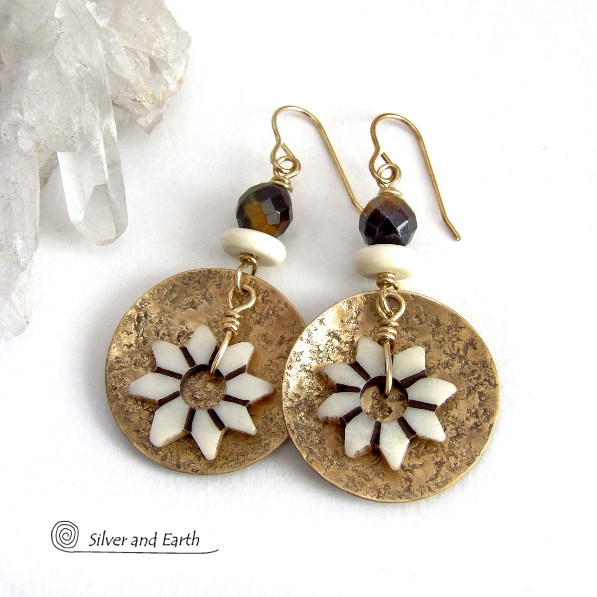 These handmade gold brass earrings have an ethnic bohemian style with an African inspired flair that makes a bold statement. They feature round brass dangles with a lightly hammered texture accented with African flower-shaped bone beads, faceted natural tiger's eye gemstones and African bone beads. Unique and fun to wear, they'll make a great gift for nature lovers and gardeners who love bohemian style jewelry. Handmade in the USA by Silver and Earth Jewelry. 