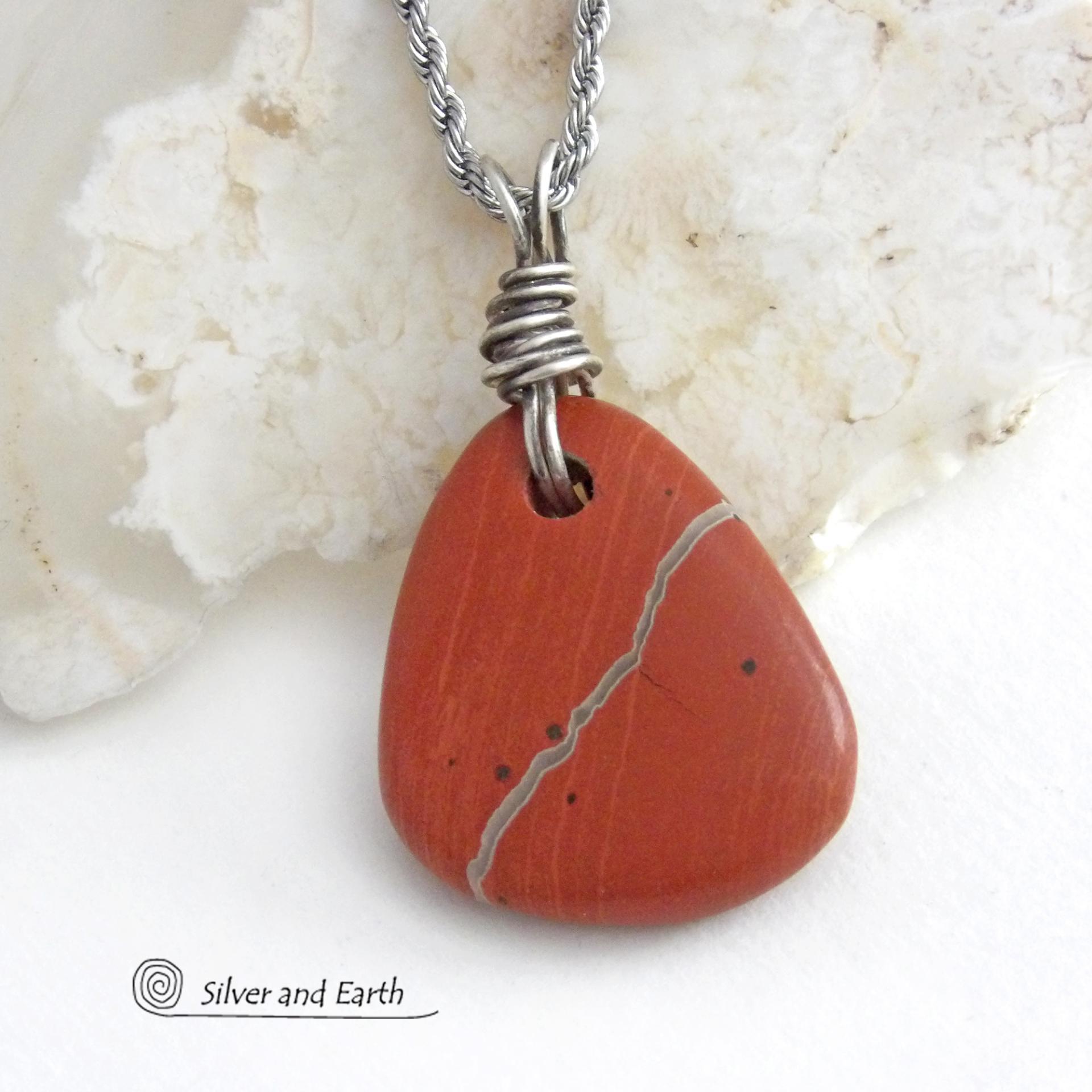 Simple and earthy - this pendant necklace features a natural red jasper gemstone with a wire wrapped sterling silver bail. The stone has a brick red hue with a natural matrix of beige streaks and dots. It has a modern minimalist appeal and is perfect for those that prefer simple, earthy jewelry that coordinates well with all wardrobe styles. It makes a great gift for a natural stone lover - or a nice addition to your own jewelry wardrobe. Handmade in the USA by Silver and Earth Jewelry. 