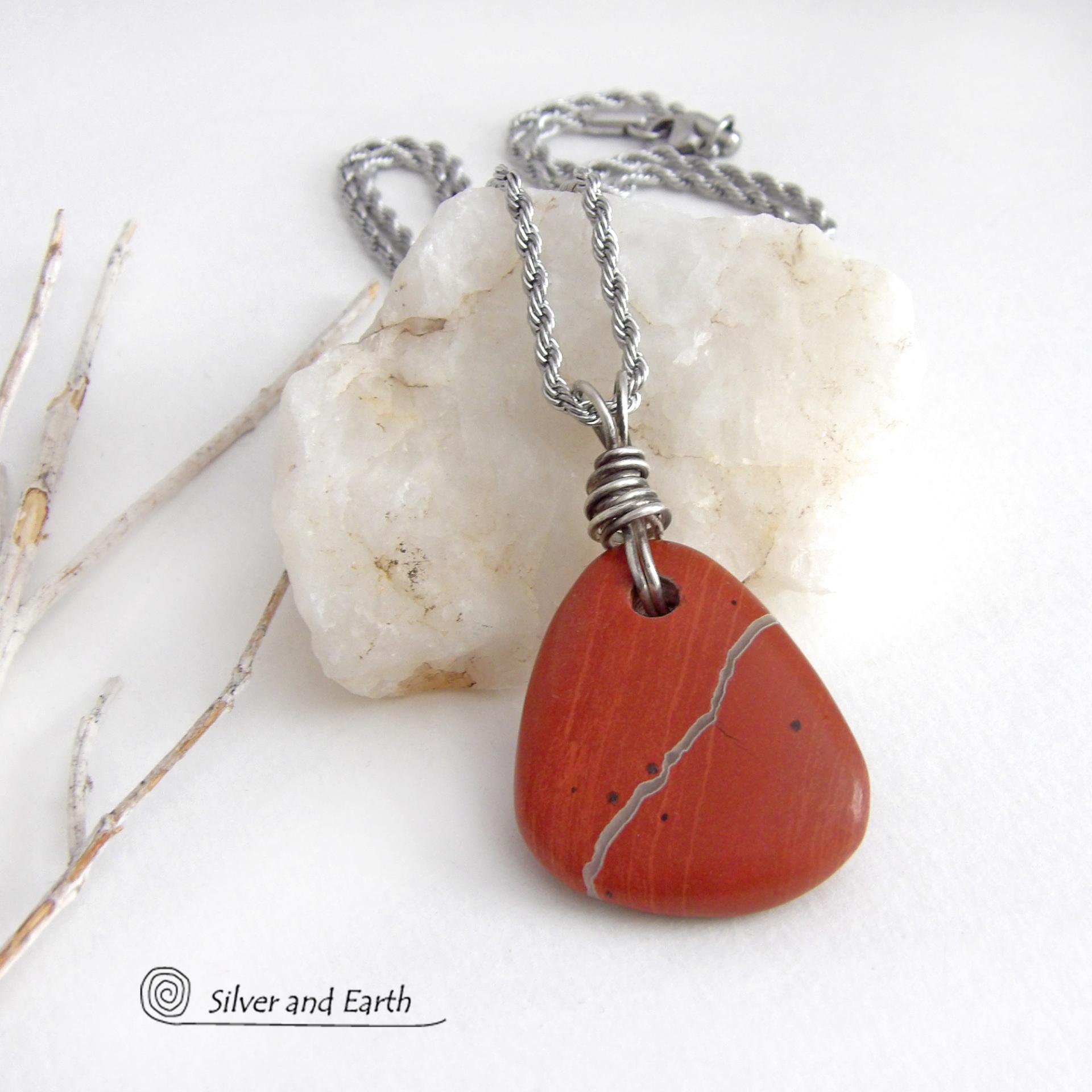 Simple and earthy - this pendant necklace features a natural red jasper gemstone with a wire wrapped sterling silver bail. The stone has a brick red hue with a natural matrix of beige streaks and dots. It has a modern minimalist appeal and is perfect for those that prefer simple, earthy jewelry that coordinates well with all wardrobe styles. It makes a great gift for a natural stone lover - or a nice addition to your own jewelry wardrobe. Handmade in the USA by Silver and Earth Jewelry. 