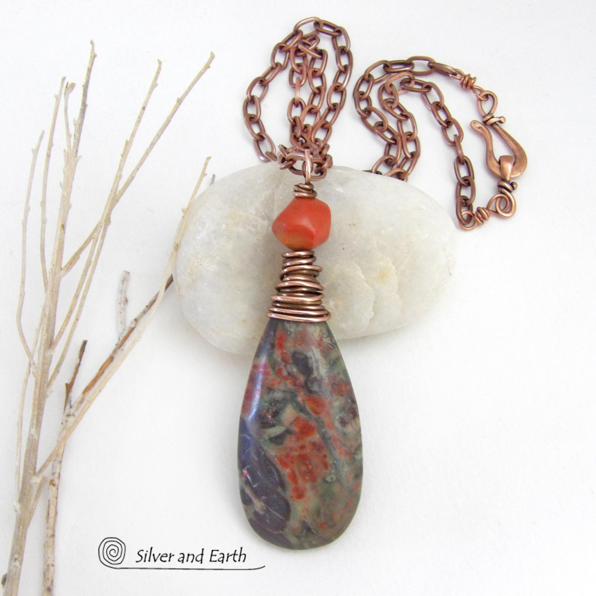 This handcrafted pendant necklace features a natural rhyolite jasper stone wire wrapped in copper wire and accented with a nugget-shaped coral bead. It has a natural pattern in several shades of earthy green along with splashes of orange. It has an earthy, casual boho style and is perfect for anyone that loves natural stones. It comes on an 18” copper chain with sturdy hook & eye closure; which can be removed from the pendant and worn alone or with other pendants in your wardrobe.