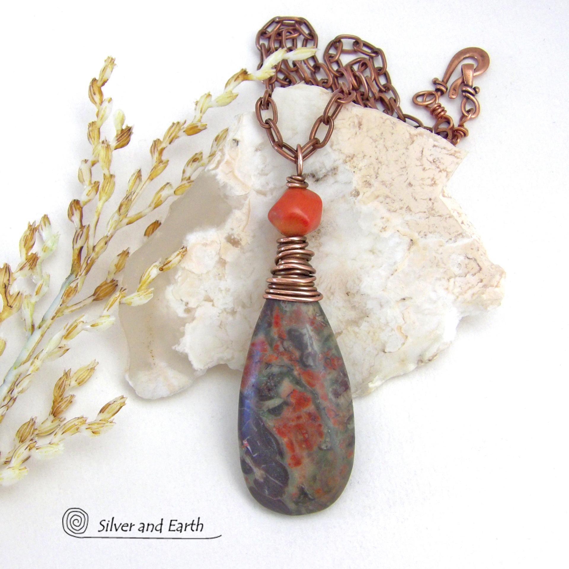 This handcrafted pendant necklace features a natural rhyolite jasper stone wire wrapped in copper wire and accented with a nugget-shaped coral bead. It has a natural pattern in several shades of earthy green along with splashes of orange. It has an earthy, casual boho style and is perfect for anyone that loves natural stones. It comes on an 18” copper chain with sturdy hook & eye closure; which can be removed from the pendant and worn alone or with other pendants in your wardrobe.
