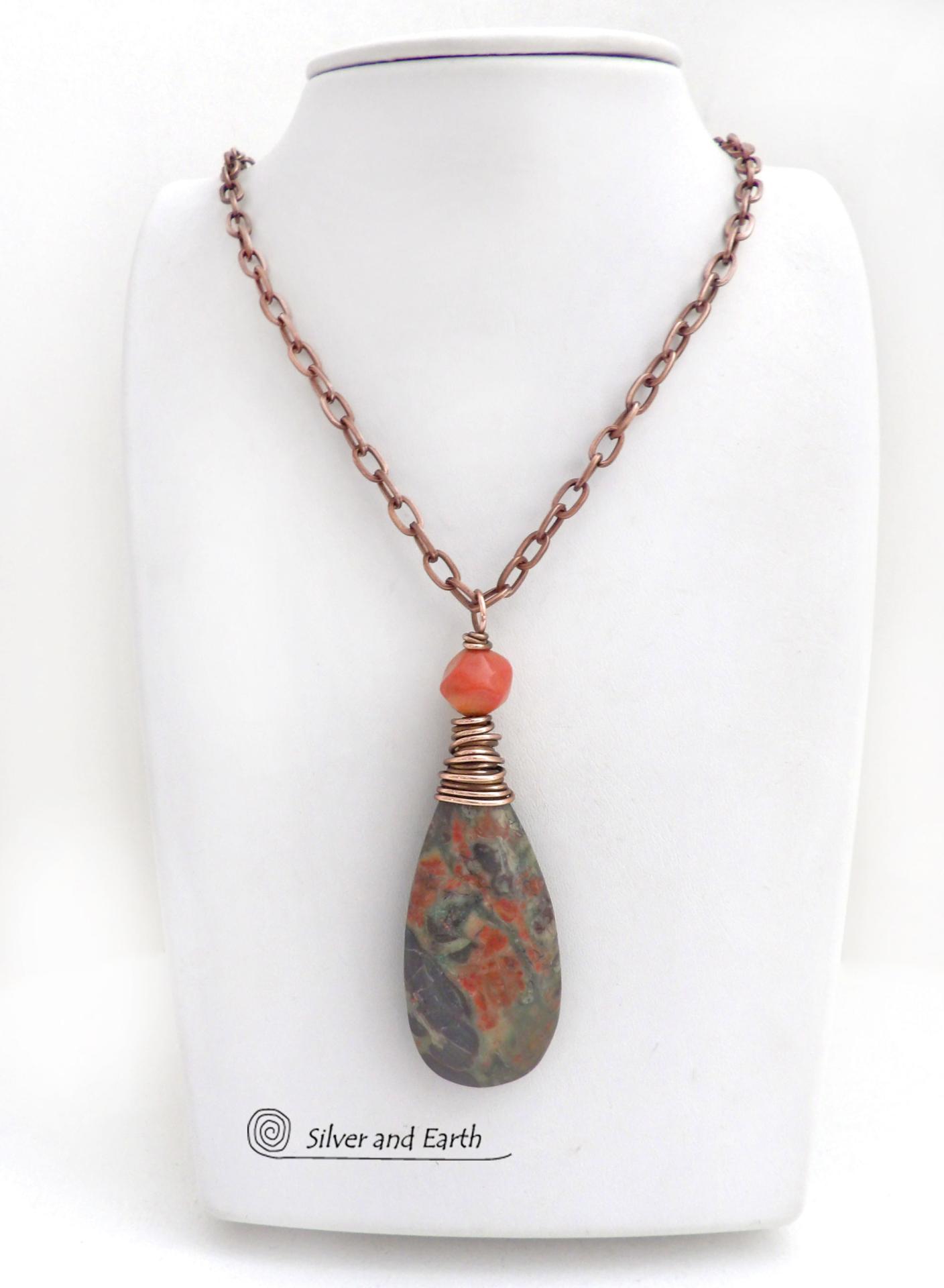 This handcrafted pendant necklace features a natural rhyolite jasper stone wire wrapped in copper wire and accented with a nugget-shaped coral bead. It has a natural pattern in several shades of earthy green along with splashes of orange. It has an earthy, casual boho style and is perfect for anyone that loves natural stones. It comes on an 18” copper chain with sturdy hook & eye closure; which can be removed from the pendant and worn alone or with other pendants in your wardrobe.