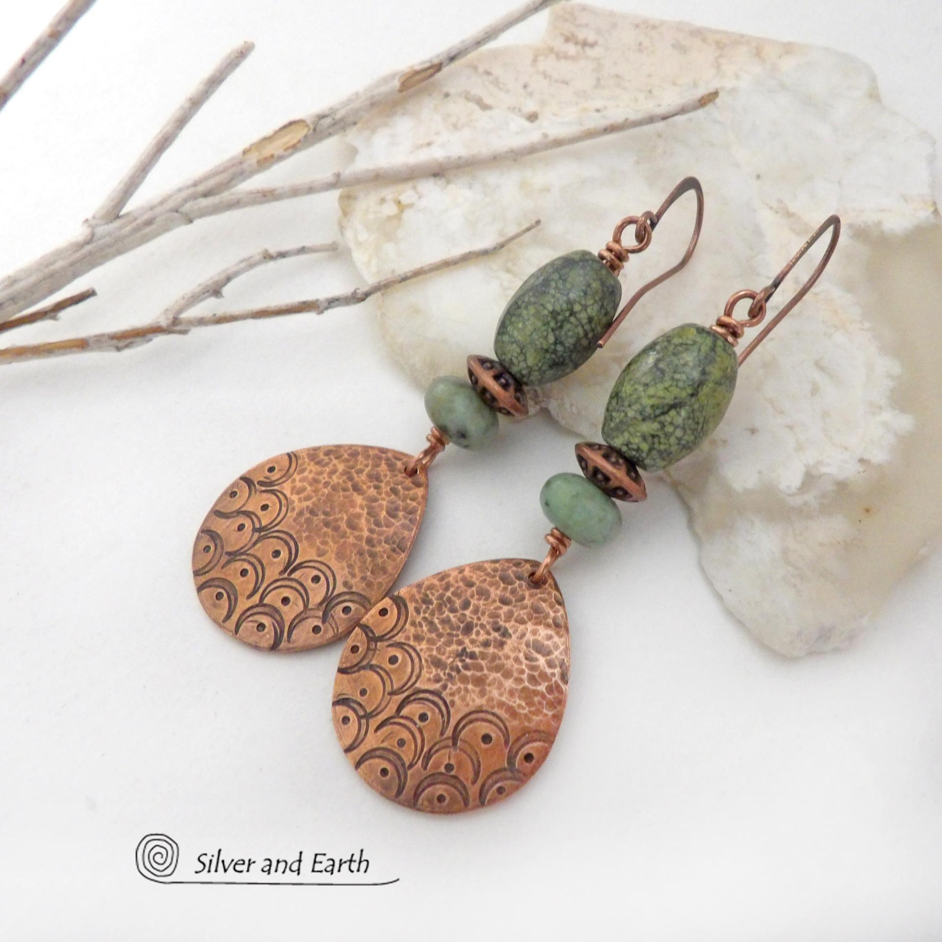These handcrafted copper earrings have a hammered and hand stamped texture and are accented with green Russian serpentine stones. Russian serpentine is known for its unique natural patterns with light and dark green speckles and web-like patterns. They are accented with small, light green African turquoise stones and copper beads. Bold and unique, they have a boho chic flair and will make a striking statement. Handmade in the USA by Silver and Earth Jewelry.
