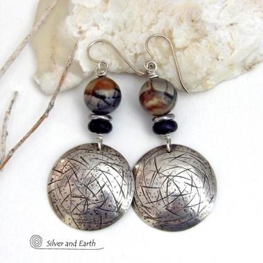 These one-of-a-kind earrings feature handcrafted sterling silver with a hammered and hand stamped texture accented with earthy natural Picasso marble gemstones, black glass and stainless steel beads. This semiprecious stone is found only in southwest Utah. It's named after the famous artist because the natural matrix of geometric lines resembles an abstract painting. The stones in this pair have a beautiful matrix pattern of distinctive swirly lines in black, grey and chocolate brown.