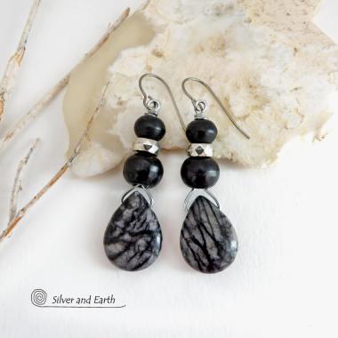 The earrings feature natural zebra jasper stones accented with black beads and silver plated beads and dangle from hypoallergenic titanium ear wires. This stone is known as zebra jasper because of the natural striped matrix that resembles a zebra's pattern. It's a striking stone with earthy hues of soft gray, along with streaks of black. They'll make a great gift for a natural stone lover - or a nice addition to your own jewelry wardrobe. Handmade in the USA by Silver and Earth Jewelry. 