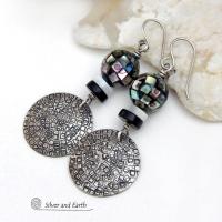 These handcrafted sterling silver earrings feature an abstract hand stamped texture and are accented with inlaid abalone shell mosaic, black onyx and mother-of-pearl beads. The abalone beads resemble disco balls and have a beautiful rainbow iridescence of various colors. Bold and unique, they have a modern contemporary style and will make a striking statement. Handmade in the USA by Silver and Earth Jewelry. Length: approx. 2-1/8” from top of sterling silver ear wires and 7/8". 