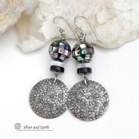 These handcrafted sterling silver earrings feature an abstract hand stamped texture and are accented with inlaid abalone shell mosaic, black onyx and mother-of-pearl beads. The abalone beads resemble disco balls and have a beautiful rainbow iridescence of various colors. Bold and unique, they have a modern contemporary style and will make a striking statement. Handmade in the USA by Silver and Earth Jewelry. Length: approx. 2-1/8” from top of sterling silver ear wires and 7/8". 