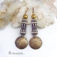 Bold and unique, these handcrafted earrings have an ethnic African tribal vibe. They feature gold brass dangles with a hammered rustic texture accented with exotic African beads with an intricate brown and white carved pattern topped off with gold brass beads. Unique and fun to wear - they'll make a bold, striking statement. Perfect for women that love to wear one-of-a-kind artisan handcrafted jewelry. Handmade in the USA by Silver and Earth Jewelry. 