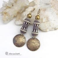 Bold and unique, these handcrafted earrings have an ethnic African tribal vibe. They feature gold brass dangles with a hammered rustic texture accented with exotic African beads with an intricate brown and white carved pattern topped off with gold brass beads. Unique and fun to wear - they'll make a bold, striking statement. Perfect for women that love to wear one-of-a-kind artisan handcrafted jewelry. Handmade in the USA by Silver and Earth Jewelry. 