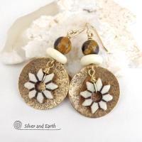 These handmade gold brass earrings have an ethnic bohemian style with an African inspired flair that makes a bold statement. They feature round brass dangles with a lightly hammered texture accented with African flower-shaped bone beads, faceted natural tiger's eye gemstones and African bone beads. Unique and fun to wear, they'll make a great gift for nature lovers and gardeners who love bohemian style jewelry.