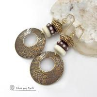 Big and bold, these handcrafted gold brass hoop earrings have a hand stamped texture and are accented with African batik bone dark brown beads with a dotted pattern, off-white bone beads and textured gold brass beads. They have an exotic ethnic and boho chic vibe that makes a striking, unique statement. Handmade in the USA by Silver and Earth Jewelry.