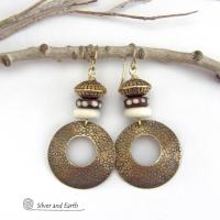 Big and bold, these handcrafted gold brass hoop earrings have a hand stamped texture and are accented with African batik bone dark brown beads with a dotted pattern, off-white bone beads and textured gold brass beads. They have an exotic ethnic and boho chic vibe that makes a striking, unique statement. Handmade in the USA by Silver and Earth Jewelry.