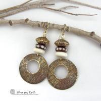 Big and bold, these handcrafted gold brass hoop earrings have a hand stamped texture and are accented with African batik bone dark brown beads with a dotted pattern, off-white bone beads and textured gold brass beads. They have an exotic ethnic and boho chic vibe that makes a striking, unique statement. Handmade in the USA by Silver and Earth Jewelry.