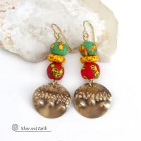 Bold and unique - these gold brass dangle earrings will surely brighten your day! They feature bright and colorful African glass beads with beautiful hues of green, red and yellow. They are accented with handcrafted gold brass dangles with a hammered organic texture. The African beads are handcrafted by artisans in Ghana from recycled glass by a traditional process passed down thru many generations. These earrings have a bohemian Afrocentric style with lots of fashionable flair! 