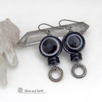 These earrings feature big natural black eye agate stones accented with black onyx and small hammered silver pewter circle dangles. When cut at the right angle, this type of agate reveals a series of concentric rings that resembles the human eye. They have a funky, modern vibe and are unique and fun to wear. They'll make a bold statement and are perfect for women that love to wear unique natural stone jewelry. 