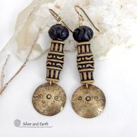 Bold and unique, these handcrafted earrings have an ethnic African tribal vibe. They feature gold brass dangles with a hand stamped and lightly hammered background texture accented with African beads with an intricately carved brownish-black and tan pattern topped off with black African carved bone beads. Unique and fun to wear - they'll make a bold, striking statement. Perfect for women that love to wear one-of-a-kind artisan handcrafted jewelry. Handmade in the USA by Silver and Earth Jewelry.