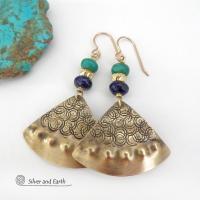 These handcrafted gold brass earrings have an exotic, Egyptian inspired vibe. The design consists of brass fan-shaped dangles with a hand textured design accented with lapis lazuli and turquoise gemstones and gold plated beads. Bold and unique, they'll add a touch of cultural exotic charm to any type of wardrobe. Handmade in the USA by Silver and Earth Jewelry, these earrings are a beautiful and stylish way to add a touch of elegance to any outfit. 