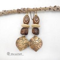 These handcrafted earrings feature gold brass dangles with a hand stamped texture accented with brown Tibetan etched agate stones, brown wood beads and tan wood saucer beads. Bold and unique, they have an ethnic tribal style with boho flair that makes a striking statement. Bold and striking, these handmade earrings are a beautiful example of bohemian-inspired jewelry.