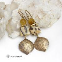 These handcrafted earrings feature shiny gold brass dangles with a hammered raw silk texture accented with graphic feldspar and golden tiger's eye gemstones and shiny brass beads. Graphic feldspar is a type of moonstone that has smoky quartz inclusions which creates unique natural patterns. They have an elegant, modern chic style that looks great dressed up or down. Handmade in the USA by Silver and Earth Jewelry. Total length of approx. 2-3/8" from top of brass ear wires and 3/4" at widest point.