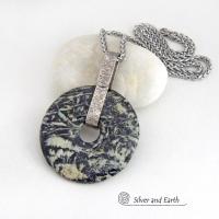 This one-of-a-kind pendant necklace features a stunning black fireworks jasper stone accented with a hand forged sterling silver bail. The stone has a natural dramatic pattern in hues of black with streaks of soft minty green and tan. The design is modern and bold - yet classic and always in fashion. It can be worn by either a man or a women. It's reversible and can be worn on either side. (See all photos for alternate sides).
