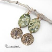 These earrings feature gold brass dangles with a rustic hammered and hand stamped texture accented with natural green rainforest jasper gemstones. They have an earthy chic, modern style that coordinates well with all wardrobe types. Rainforest Jasper is a gemstone that belongs to the rhyolite family. It's known for its vibrant patterns and earthy tones featuring a mix of greens, browns, and cream. These colors form beautiful and intricate patterns which resemble the lush, diverse vegetation of a tropical ra