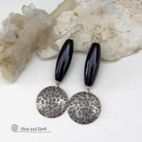 These handcrafted sterling silver dangle earrings have a hand stamped texture and oxidized finish and feature long black onyx gemstones. The stones are cut into a unique, elongated tubular shape and have a rich black hue and high polish. They have a modern, contemporary style that will look great with all wardrobe types. 