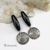 These handcrafted sterling silver dangle earrings have a hand stamped texture and oxidized finish and feature long black onyx gemstones. The stones are cut into a unique, elongated tubular shape and have a rich black hue and high polish. They have a modern, contemporary style that will look great with all wardrobe types. 