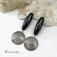 These handcrafted sterling silver dangle earrings have a hand stamped texture and oxidized finish and feature long black onyx gemstones. The stones are cut into a unique, elongated tubular shape and have a rich black hue and high polish. They have a modern, contemporary style that will look great with all wardrobe types. 