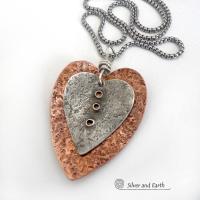 This mixed metal heart necklace has an earthy, rustic charm and will make a great gift for someone special. It features nesting hearts handcrafted from sterling silver and copper. It comes on a 20" stainless steel chain with lobster claw closure. The necklace holds a special significance as it represents two hearts coming together in union. This could be a meaningful gift for someone you love deeply.