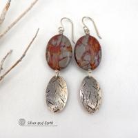 These handcrafted one-of-a-kind earrings feature natural Noreena jasper gemstones accented with textured sterling silver dangles. This stone is known for its dramatic abstract and geometric patterns and is found only in the Pilbara region of Western Australia. The stones in this pair have a great pattern consisting of hues of deep burgundy-red with fiery orange and gray streaks. They'll make a great gift for women that appreciate and love unique natural stones. Handmade by Silver and Earth.