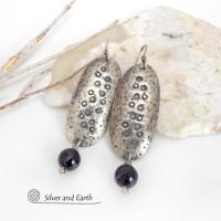 These handcrafted sterling silver earrings have a long oval shape with a hammered and hand stamped texture. Black onyx gemstones dangle from the bottom. They have a modern, earthy organic vibe that coordinates well with all wardrobe styles. Earrings are handmade in the USA by Silver and Earth Jewelry. 