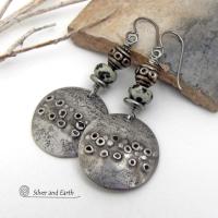 These handcrafted silver pewter earrings have a rustic, hand textured design and are accented with natural dalmatian jasper gemstones, stainless steel and vintage silver tone metal beads. They have an earthy, edgy organic style that makes a unique statement.This type of jasper is known for its spotted pattern that resembles the Dalmatian breed of dog. The matrix consists of mineral inclusions of brown iron oxide, black tourmaline & other minerals which create the natural "spots" in the stone. Handmade in th