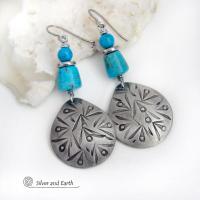 These handcrafted earrings feature silver pewter teardrop-shaped dangles with a hand stamped texture accented with natural turquoise stones and stainless steel spacer beads. They have a bold modern style with southwestern flair and will make a striking statement. They'll make a great gift for anyone that loves natural turquoise stones and southwest style jewelry. Handmade in the USA by Silver and Earth Jewelry, a New Mexico True Certified business. 