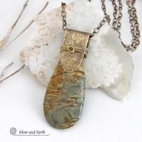 This handcrafted necklace features a natural Picasso jasper gemstone accented with a gold brass bail. The stone has a beautiful matrix with earthy hues of soft yellow, light mossy green and brown streaks. It has an earthy, modern style that coordinates beautifully with all wardrobe types. Unique and one of a kind, it makes a great gift for a natural stone lover - or a nice addition to your own jewelry collection. Comes on a 20" antiqued brass chain with lobster claw closure. 