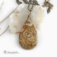 This one-of-a-kind necklace features a natural picture jasper stone wrapped in gold brass wire. The stone has an interesting matrix pattern with earthy hues of brown, tan and black. It has an earthy, simple style that coordinates beautifully with all wardrobe styles. It makes a great gift for a natural stone lover - or a nice addition to your own jewelry collection. Handmade in the USA by Silver and Earth Jewelry. Coordinating earrings sold separately.